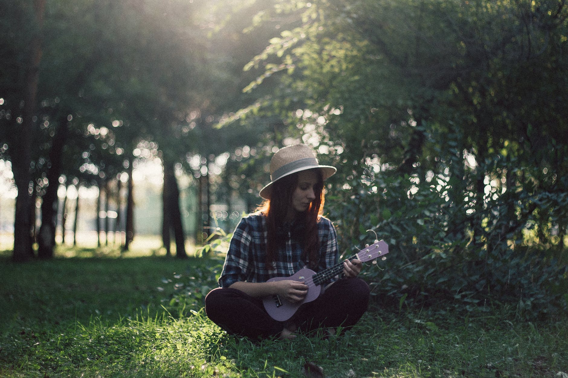 woman sitting on grass playing ukulele